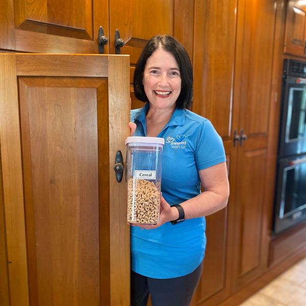 Woman holding a cereal container in a wooden kitchen.