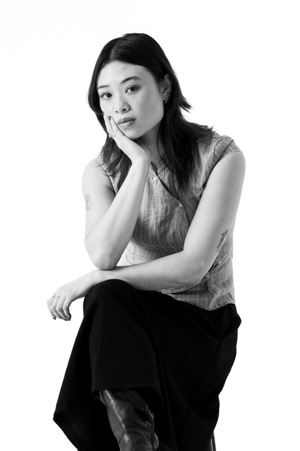 Black and white portrait of a thoughtful young woman sitting with her hand on her face.