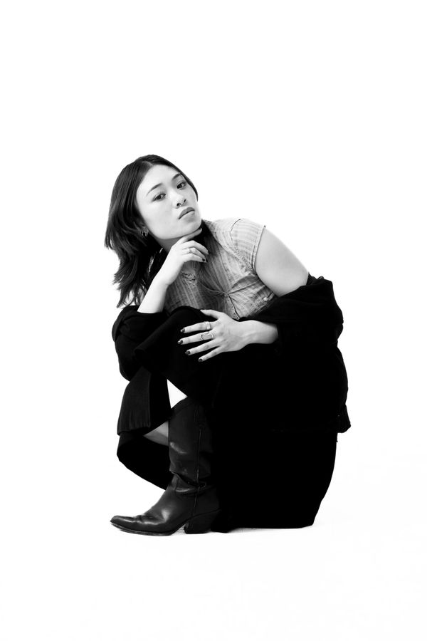 Black and white portrait of a woman crouching with a thoughtful expression.
