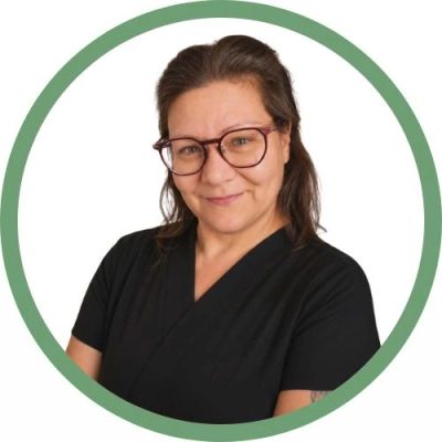 Portrait of a smiling woman wearing glasses and a black top within a green circular frame.
