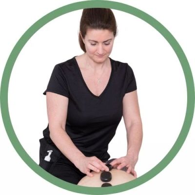 Une femme fait un massage avec des pierres chaudes.