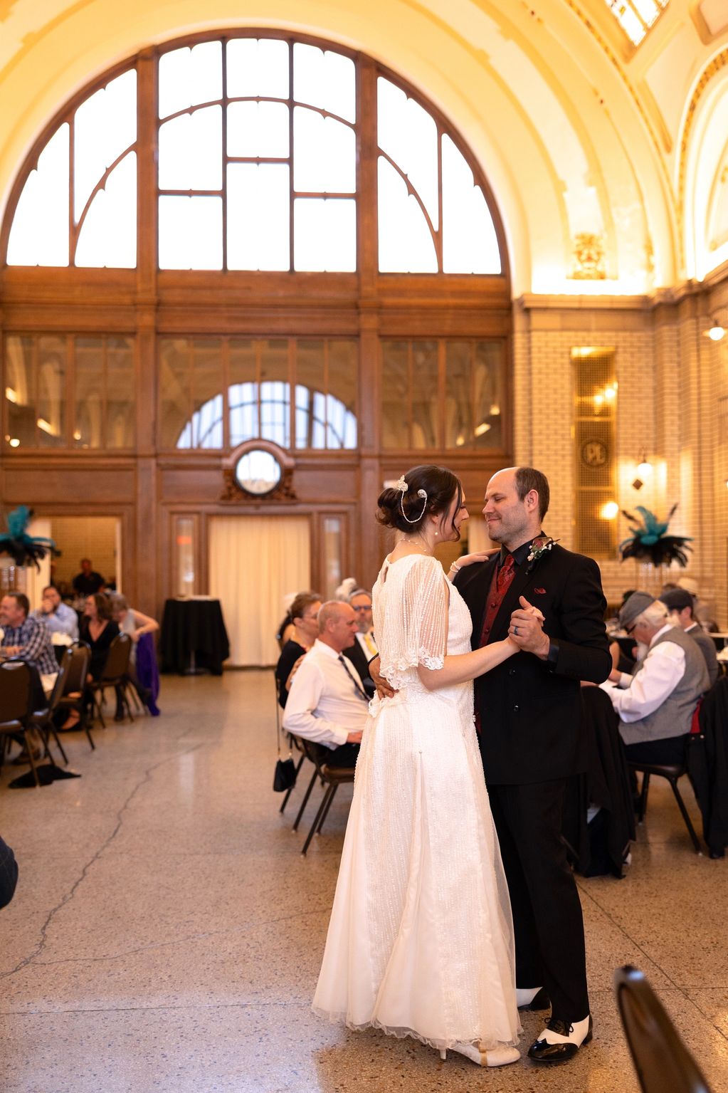 Bride and groom dancing in a grand hall.