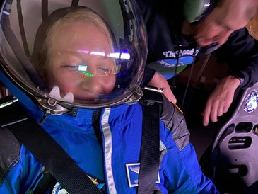 A person in a blue astronaut suit with a helmet on.