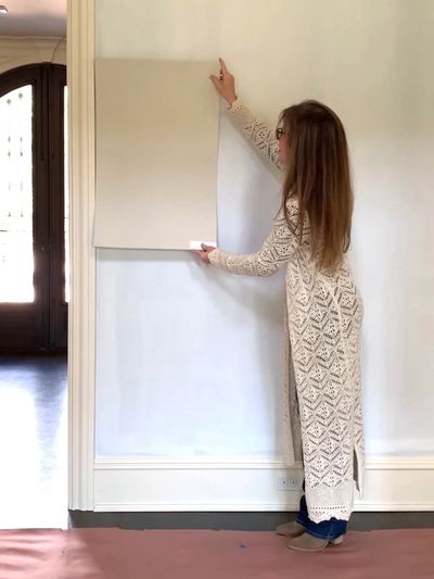 Susan Grant paint color consultant Color envy design holding a paint sample against the wall