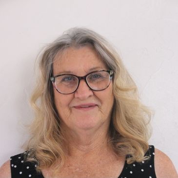 Smiling elderly woman with glasses and wavy gray hair.