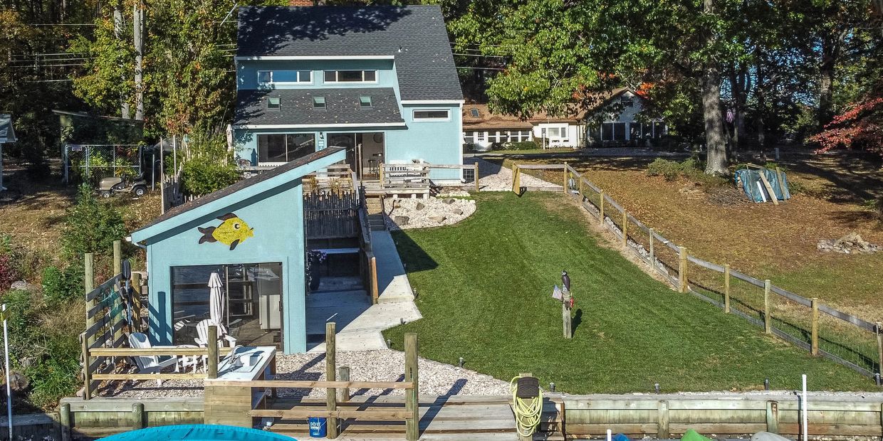 View of property from the water.  House, fenced in back yard and fish house.