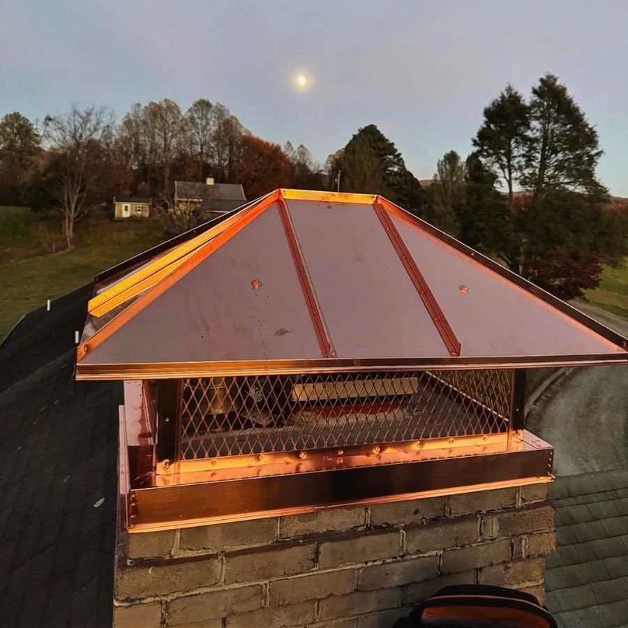 Custom copper chimney cap installation in Staunton VA on a brick chimney, with a hip-style top