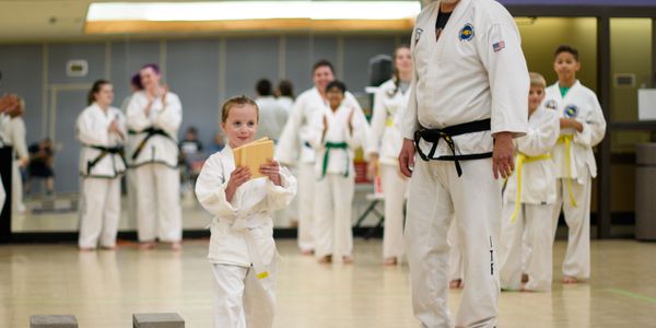 Young martial arts student holding certificates in class.
