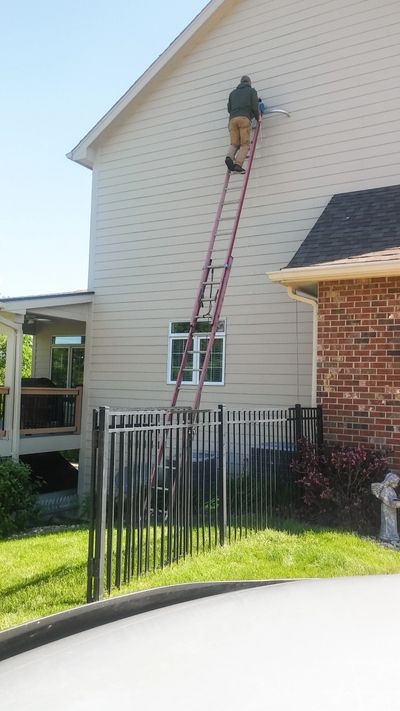 worker on a ladder cleaning out a bathroom vent from birds