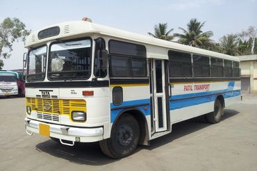 White and blue Tata bus parked outdoors with 'Patil Transport' signage.