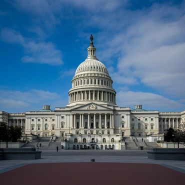 The United States Capitol building under a partly cloudy blue sky.