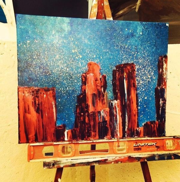 Abstract cityscape painting with red buildings under a starry blue sky.