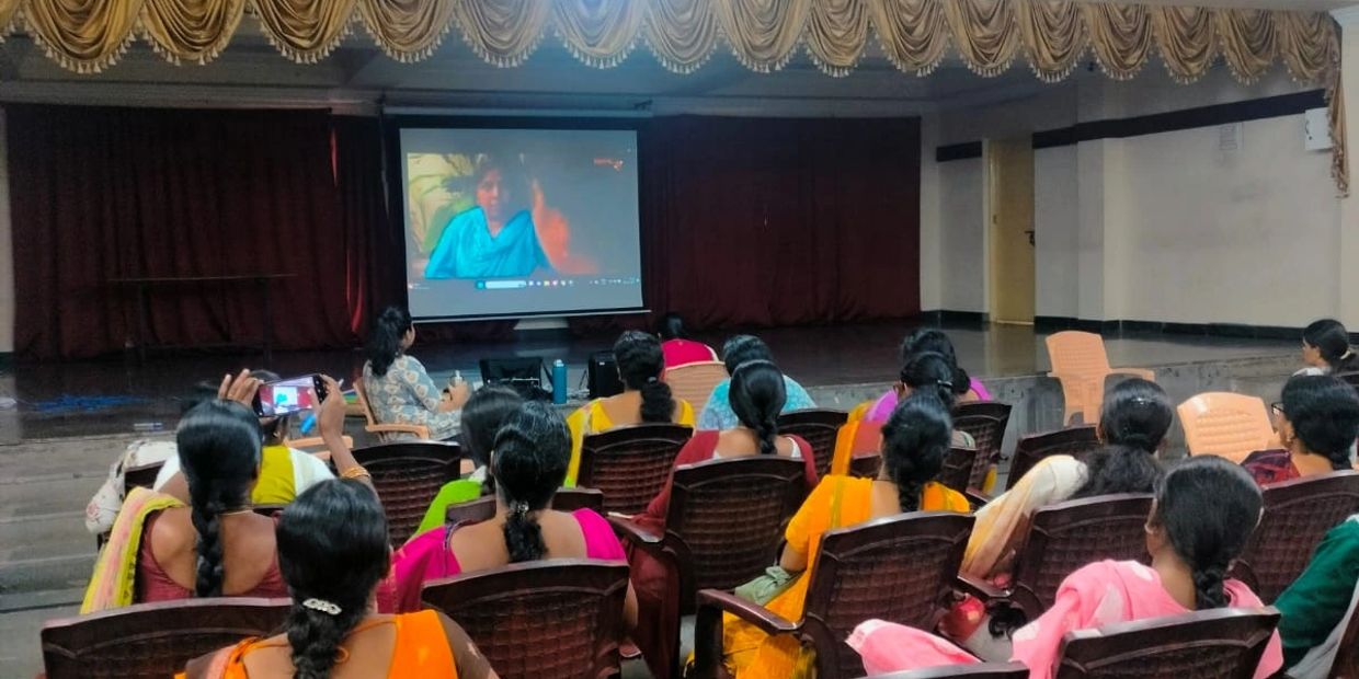 A group of women watching a video presentation in an auditorium.