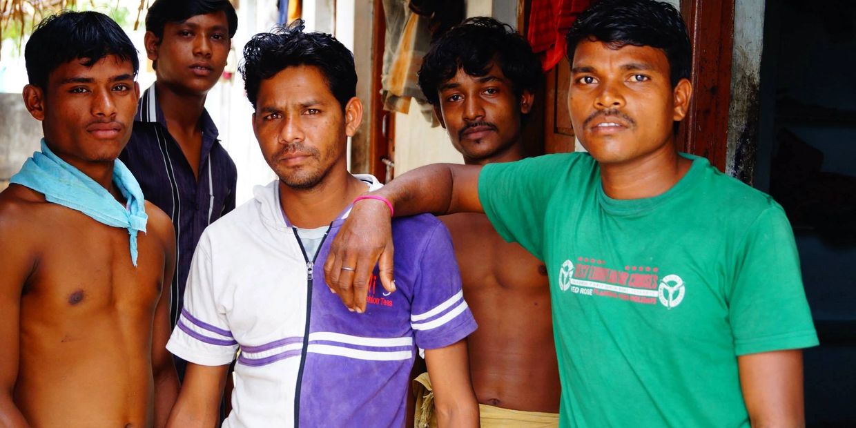 Five young men posing together in a casual setting.