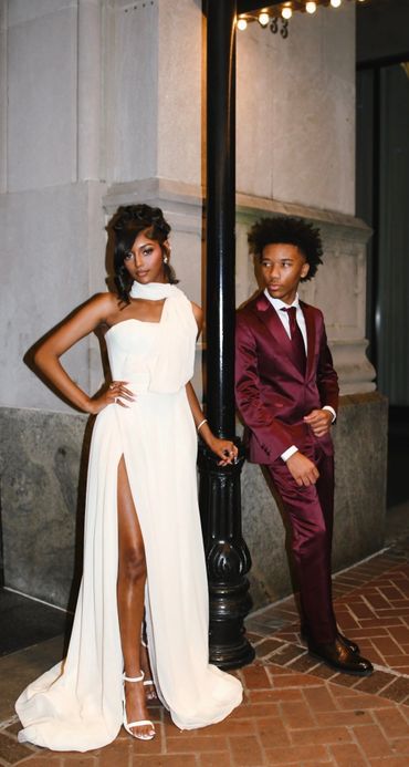 Elegant couple dressed for a formal event, posing by a lamppost.