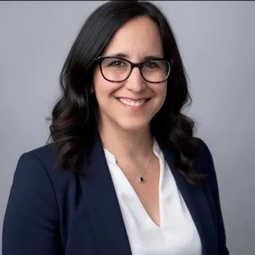 Professional woman with glasses smiling in business attire.