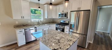 Kitchen with white shaker cabinets, stainless steel appliances and granite countertops.
