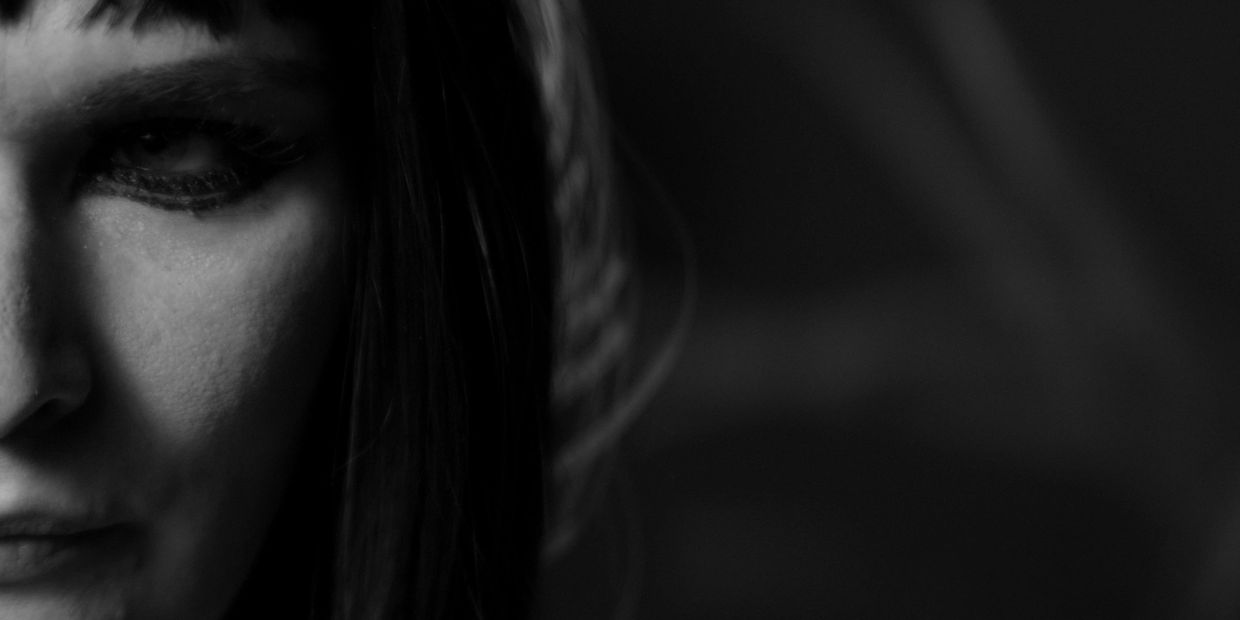 Close-up black and white portrait of a person's face with intense eye makeup.