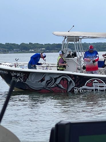 People fishing on a decorated boat on calm water.