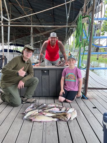 Three people displaying their fishing catch on a dock.