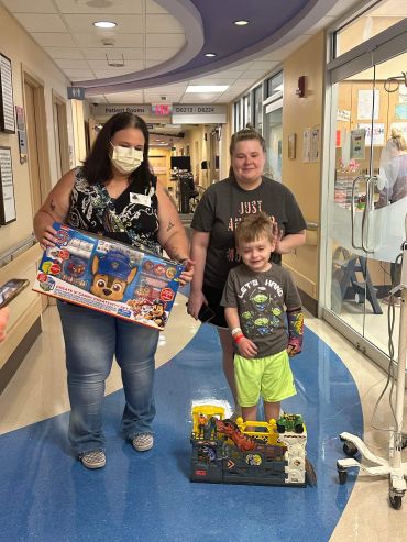 Three people in a hospital hallway with toys.