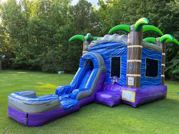 Inflatable bounce house with slide, designed like a tropical palm tree island.