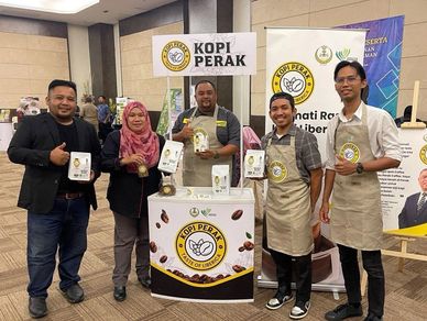 Group of five people showcasing Kopi Perak coffee at an event booth.