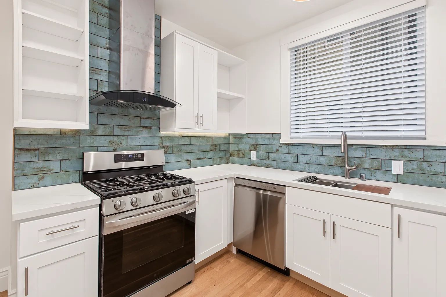 Modern kitchen with blue tile backsplash and stainless steel appliances.
