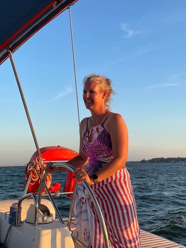 Smiling woman at the helm of a sailboat at sun down