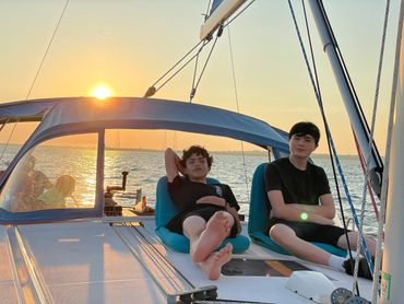 Two boys lounging on sailboat at sun down