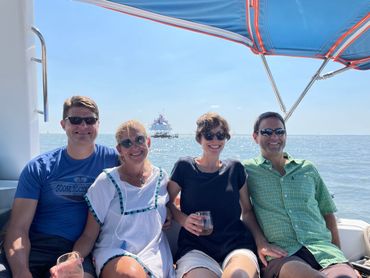 Group of friends smiling on sailboat with Thomas Point Lighthouse in the background