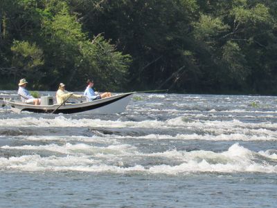 Fly fishing guide maneuvering a drift boat through Hiwassee River shoals