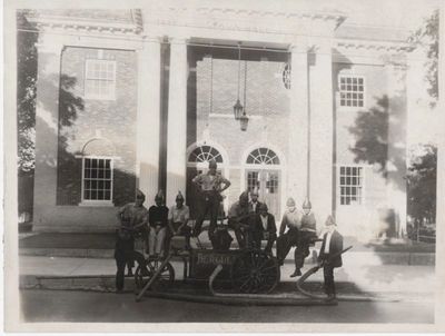 Members of the Hercules Hose Co. No. 1 pose in front of a hand pump parked in front of old Town Hall