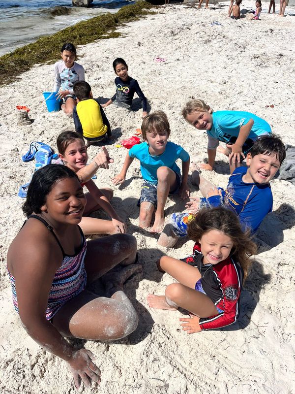 Group of children playing and having fun on a sandy beach under the sun.