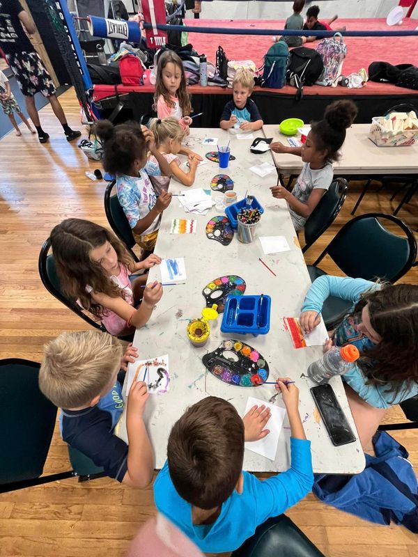 Children painting at a table with colorful palettes and brushes.
