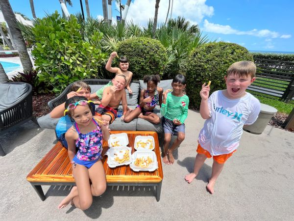 A group of kids enjoying fries by the pool on a sunny day.
