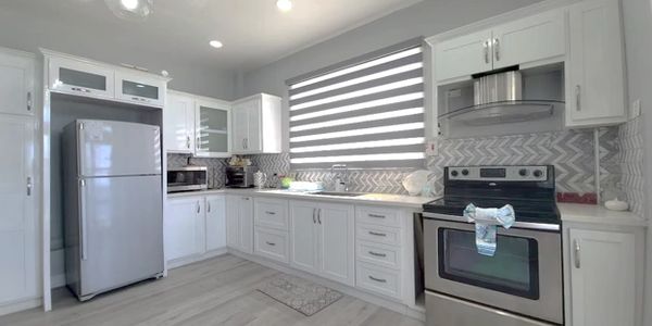 Bright white kitchen with modern appliances and patterned backsplash.