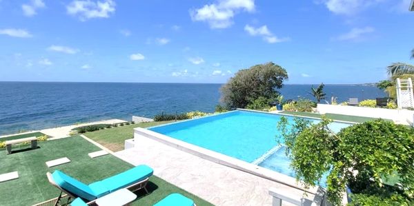 A beautiful infinity pool overlooking the ocean under a clear blue sky.