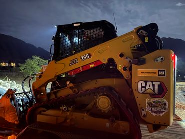 A CAT 255 construction vehicle illuminated at night.