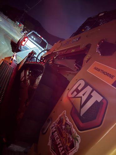 Nighttime shot of a CAT construction vehicle loaded on a trailer.
