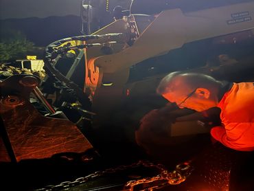 Man working on heavy machinery at night with focused lighting.