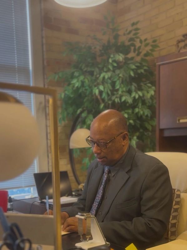 A man in a suit writing at his office desk.