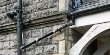 Old stone building with black metal pipes running along the wall.