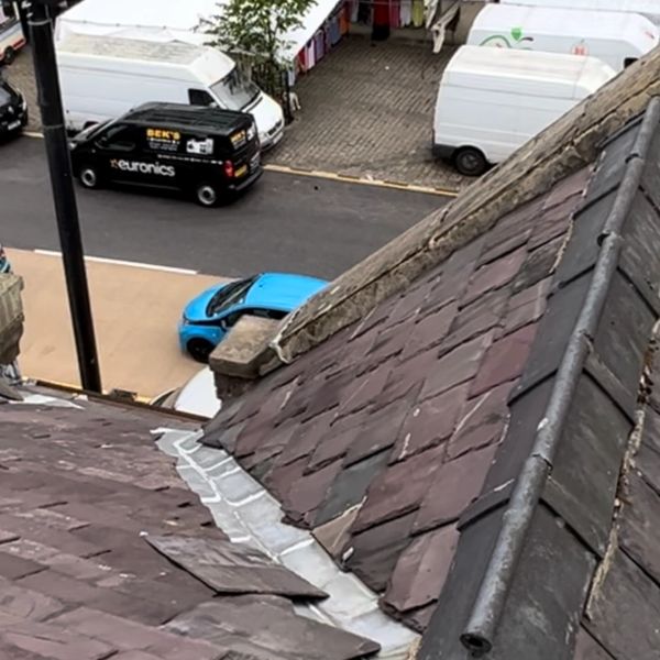Rooftop view overlooking a small street market with vans and old buildings.