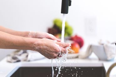 Persona lavando sus manos y fruta con agua purificada del grifo