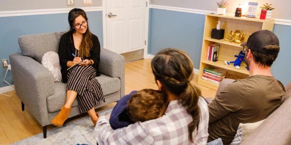 Family counseling session with a therapist taking notes.