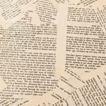 Scattered pages with printed text arranged randomly on a surface.