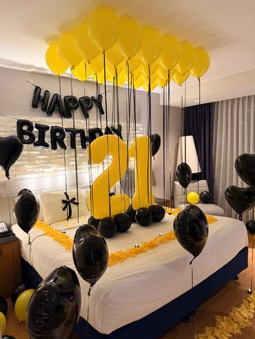 Birthday party room decorated with yellow and black balloons.