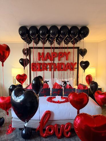 Black and red balloons decorate a birthday bed setup.