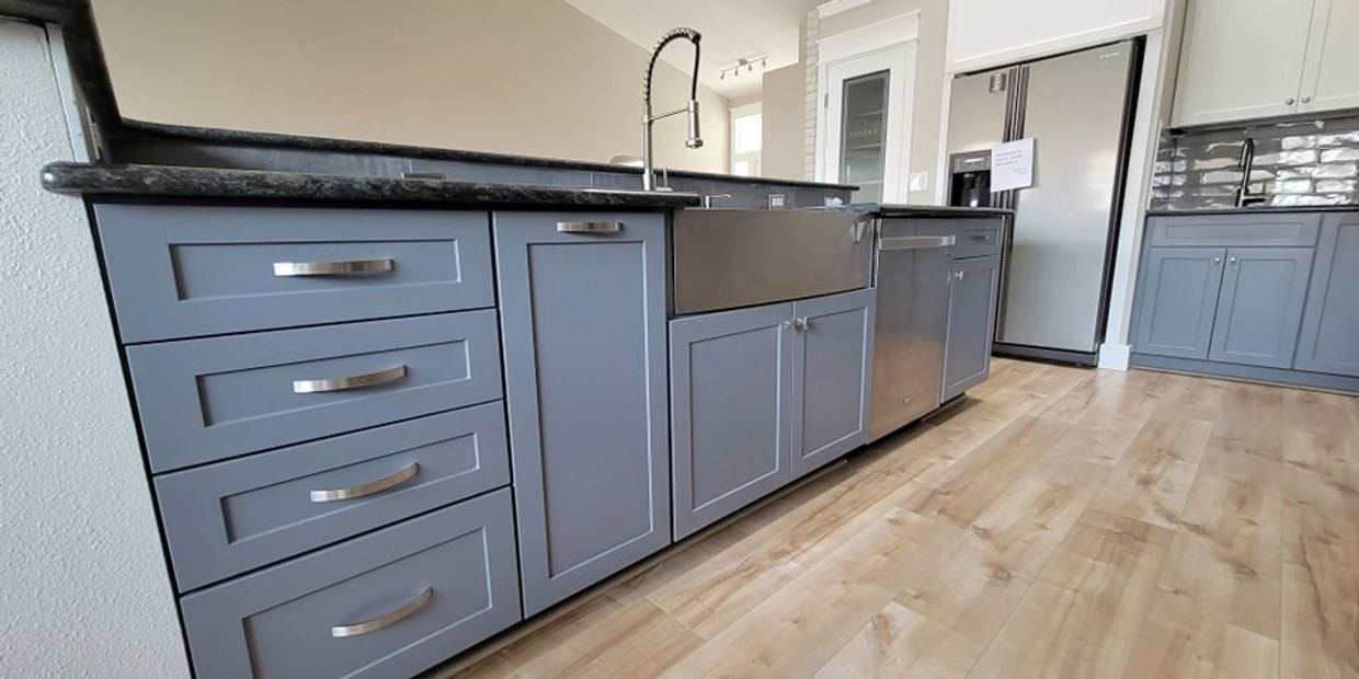 Kitchen cabinets and drawers painted in a blue gray color with beautiful matching hardware.